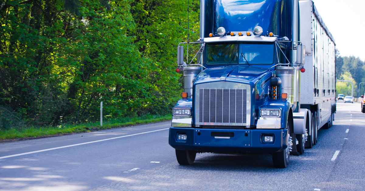 A blue semi truck driving on the highway.